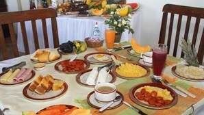 A breakfast table with various dishes, including fruits, eggs, and bread. - Pousada Gitana (Parnamirim)