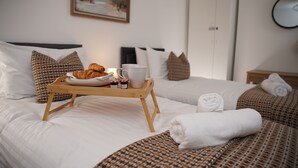 Una camera d'albergo con due letti, un vassoio con croissant e marmellata, una tazza bianca e asciugamani piegati con cura.
