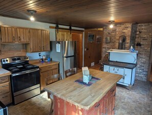 Eine Küche mit Holzausstattung, einem Edelstahlkühlschrank, einem Herd und einer Ziegelwand.