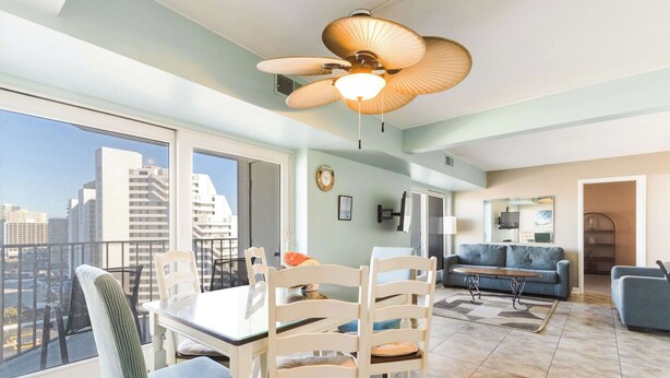 Uma sala de estar espaçosa com uma mesa de jantar, cadeiras, um sofá e um ventilador de teto.