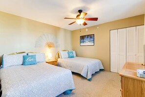 A bedroom with two beds, a ceiling fan, a nightstand, a lamp, a framed picture, and a closet. - 9400 Building #1301 (Ocean City)