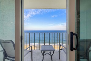A balcony with a table and chairs, overlooking a beach and the ocean. - Quay 2008, Ocean front 3 bedroom condo (Ocean City)