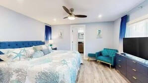 Une chambre à coucher avec un lit, un ventilateur de plafond, une télévision et une armoire.