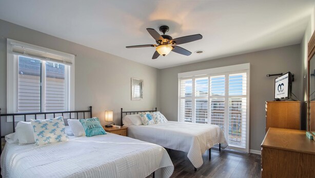 A bedroom with two beds, a ceiling fan, and a nightstand with a lamp. - Club Ocean Villa II 119 (Ocean City)