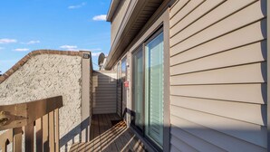 A narrow wooden deck with a brick wall on one side and a sliding glass door on the other. - Club Ocean Villa II 119 (Ocean City)