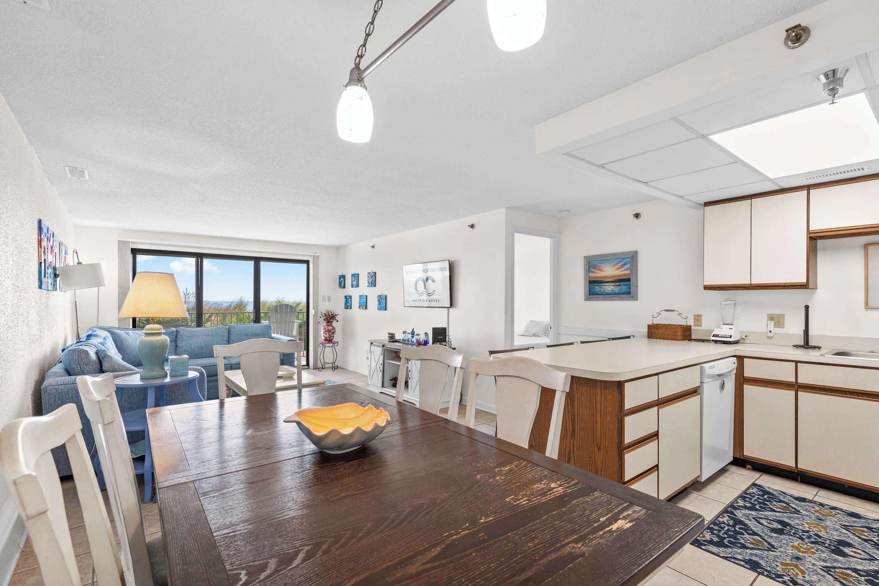 A modern kitchen with a dining area, white cabinetry, and a view of the outdoors.