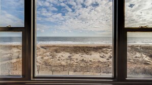 A view through a window of a beach with a wooden fence and a clear sky. - Diamond Beach 305 (Ocean City)
