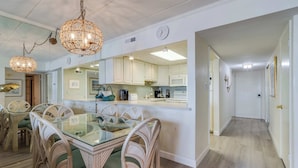 A modern kitchen with a glass dining table, wicker chairs, and pendant lights. - Diamond Beach 305 (Ocean City)