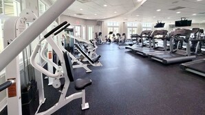 Et fitnesscenter med diverse træningsmaskiner, store vinduer og et loft med indbyggede lys.