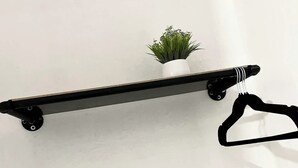Una pràctica estant de metall negre amb una petita planta en test.