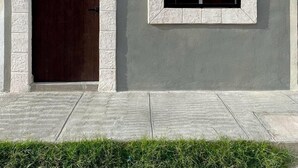 Un edifici amb una porta de fusta fosca i una finestra amb reixes negres.
