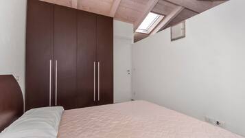 Een slaapkamer met een bed, een garderobe en een dakraam.