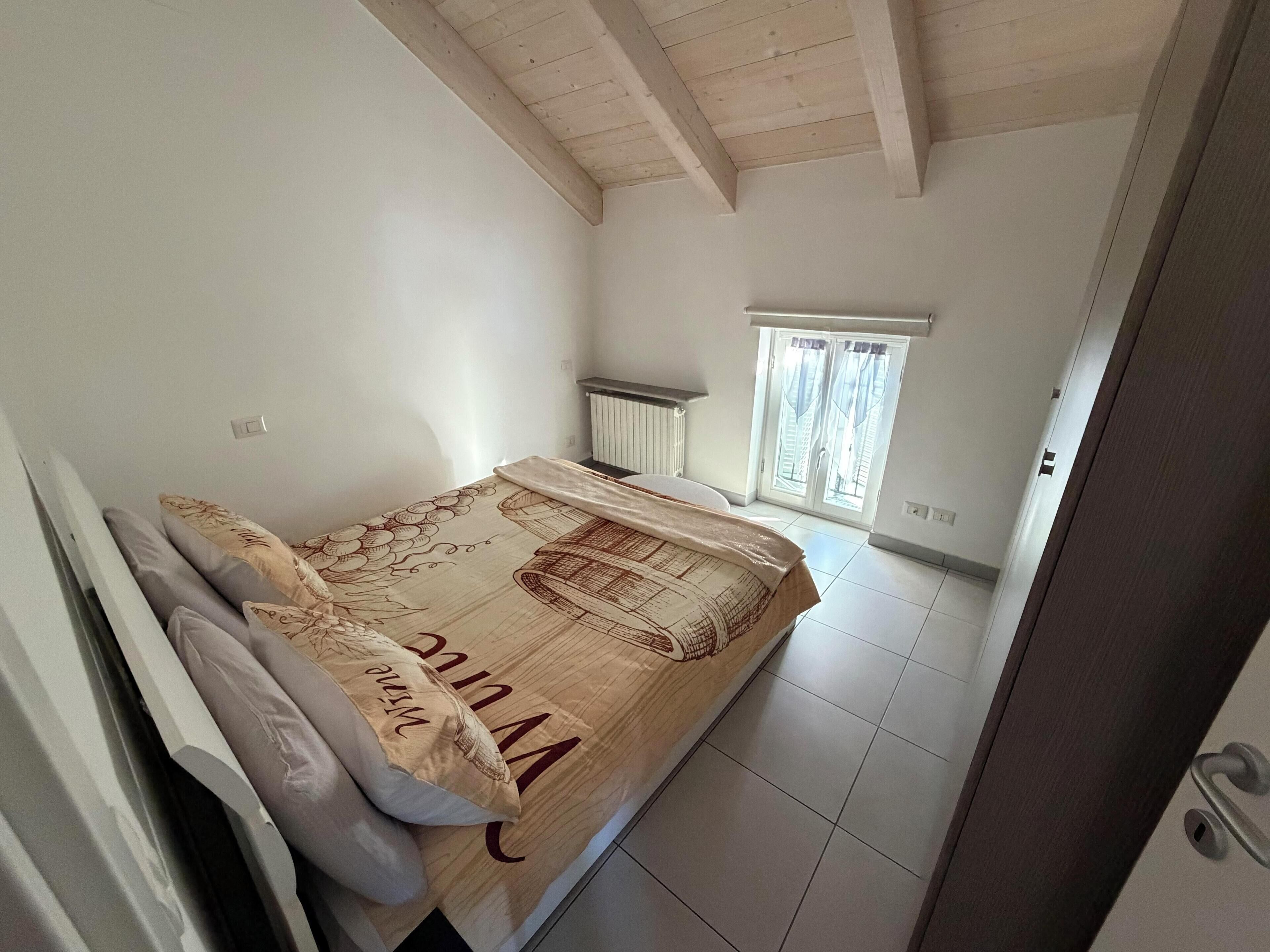 A small, clean room with a bed, a radiator, and a window.