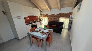 A compact living space with a kitchen, dining area, and a sofa. - Casa a Pollenzo (Pollenzo)
