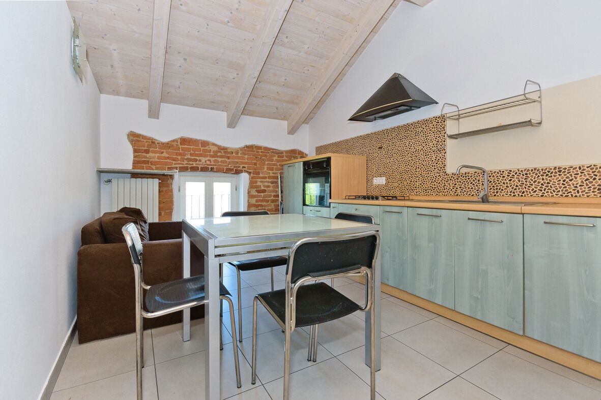 A compact kitchen with a dining area, featuring a brick wall, a modern stove, and a built-in oven.