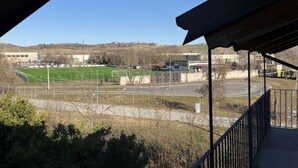 A view from a balcony overlooking a sports field, a road, and distant buildings. - Casa a Pollenzo (Pollenzo)
