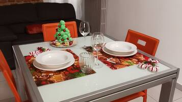 A dining table set with plates, glasses, and a Christmas tree decoration.