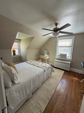 A bedroom with a bed, a ceiling fan, a radiator, a window, and a small table with a mirror. - The Blue House, a 4-bedroom house in beautiful Lynchburg central location (Lynchburg)