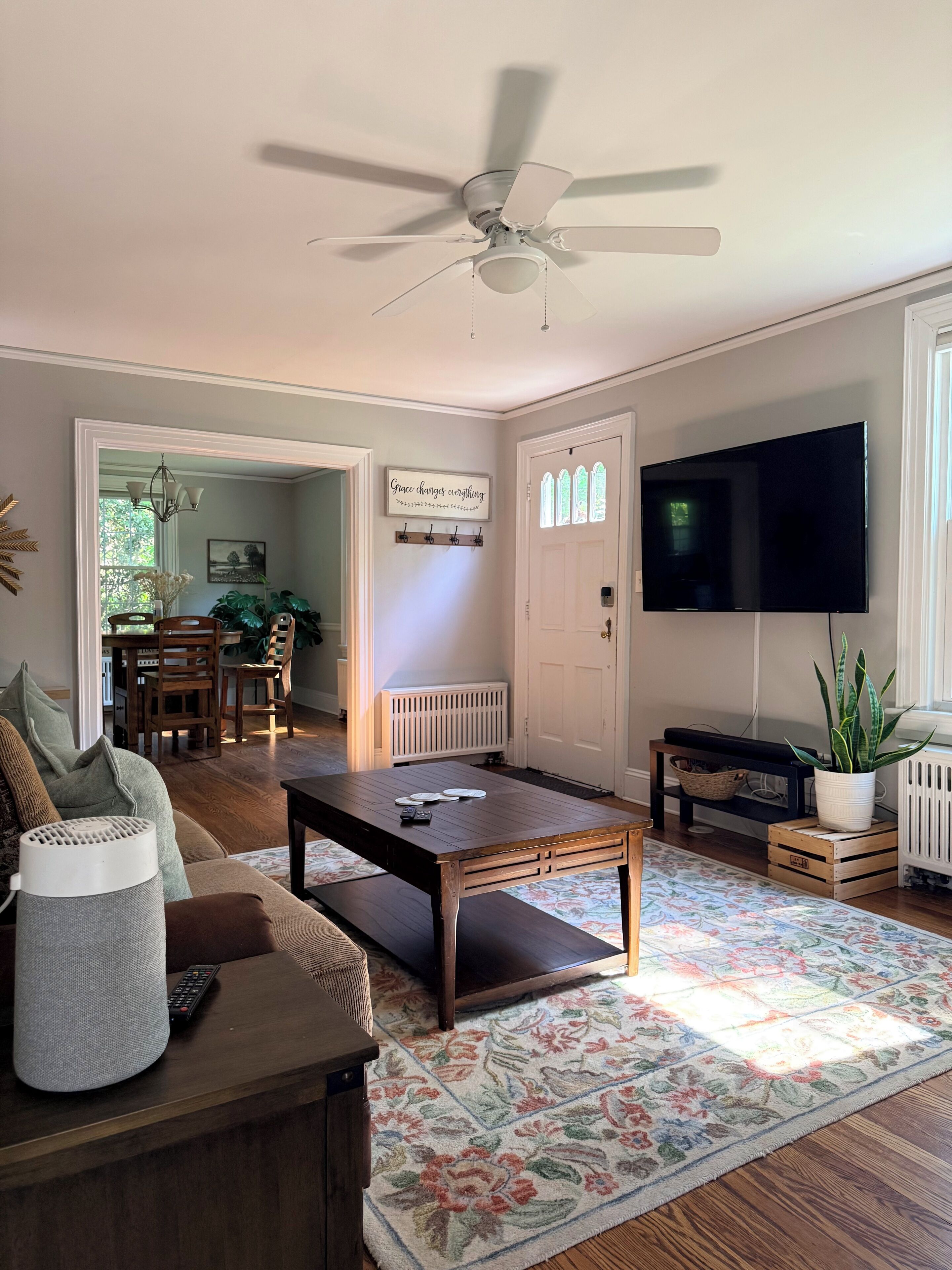 A living room with a ceiling fan, a television, a coffee table, a sofa, and a patterned rug.