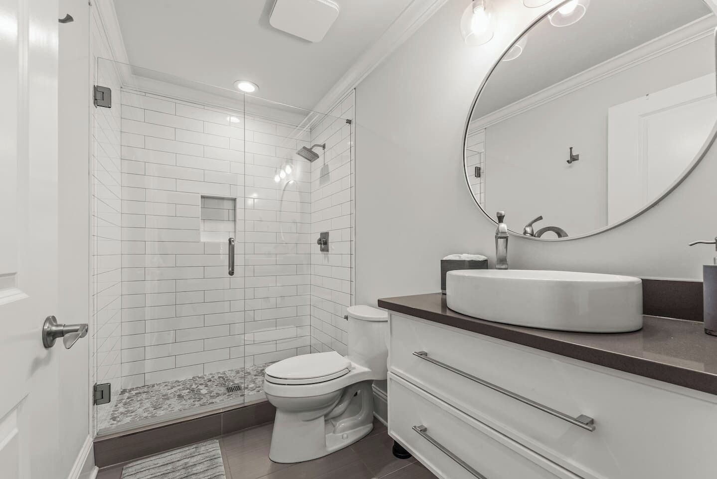 A modern bathroom with a shower, toilet, and vanity with a sink and mirror.