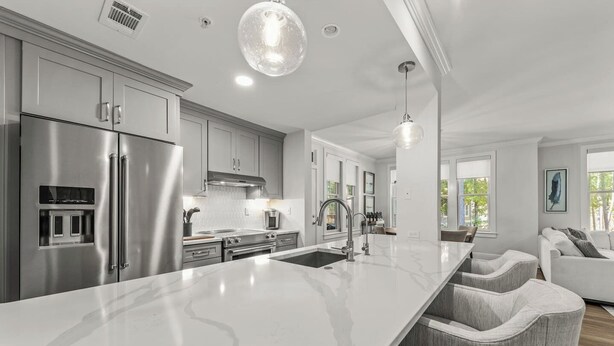 Una cocina moderna con una isla grande, electrodomésticos de acero inoxidable y vistas al área de estar.