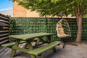 A picnic table with a hanging chair in a garden area. - Bright OTR Loft - Walk to Rhinegeist and Free Parking (Cincinnati)