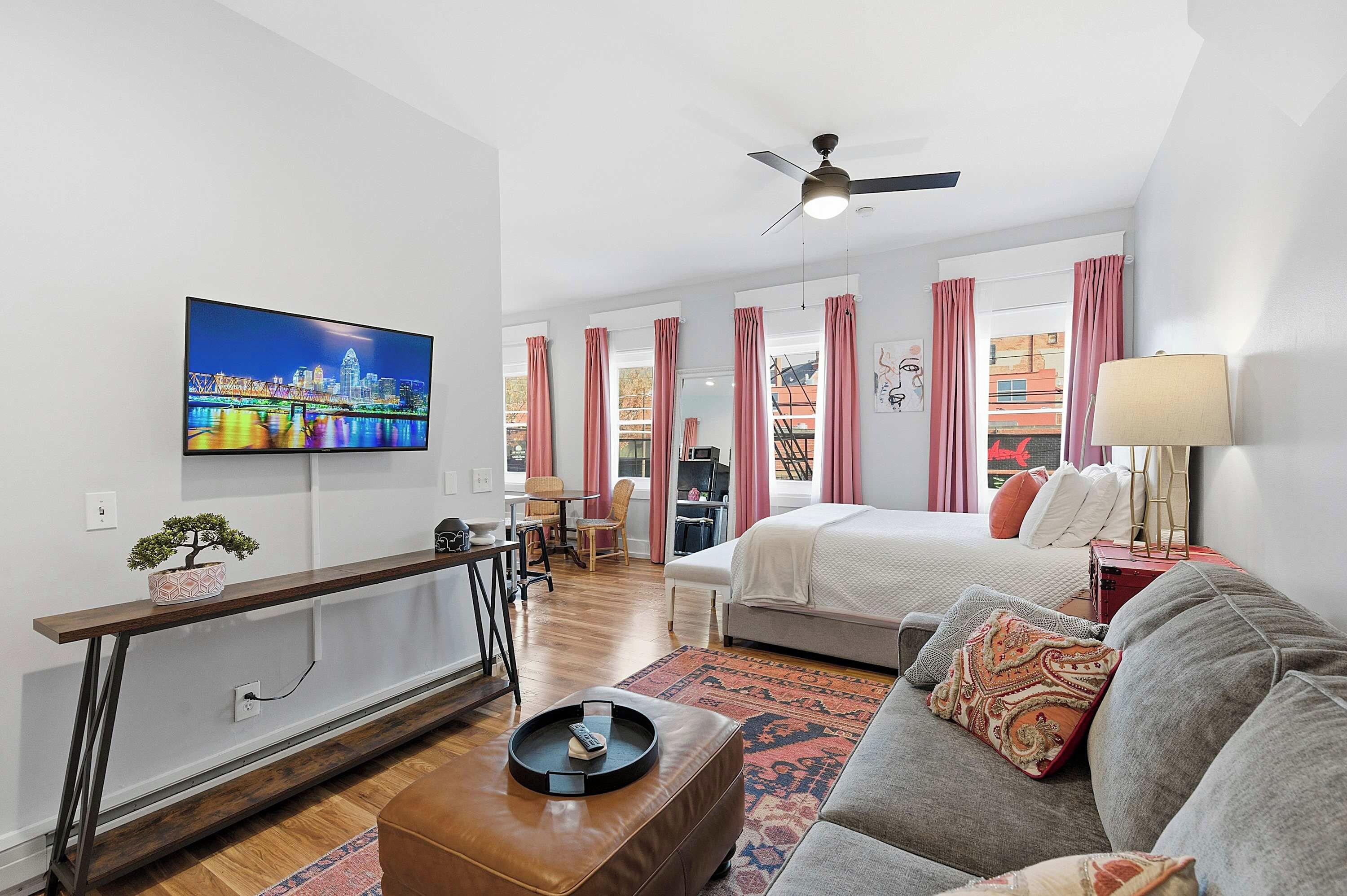 Una sala de estar moderna con un televisor de pantalla plana, un sofá, una mesa de centro y un comedor con mesa y sillas.