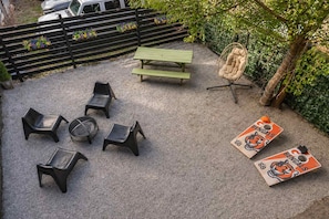 A patio area with a picnic table, chairs, a wicker chair, and two playing cards. - Bright OTR Loft - Walk to Rhinegeist and Free Parking (Cincinnati)