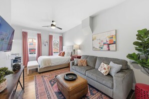 Un salon moderne avec un canapé, un pouf et un lit doté d’une tête de lit.