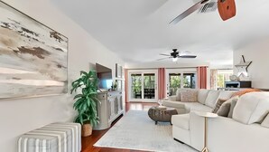 A spacious living room with a white sofa, a coffee table, and a large painting on the wall. - Sunny Tropical 3BR/3BA Retreat With Private Pool in Bonita Springs (Bonita Springs)