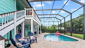 A covered outdoor area with a pool, blue chairs, and a staircase leading to a balcony. - Sunny Tropical 3BR/3BA Retreat With Private Pool in Bonita Springs (Bonita Springs)