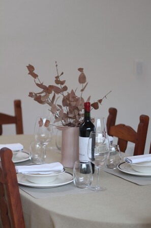 A dining table set with plates, glasses, and a bottle of wine. - Family Chalet Boutique (Luján de Cuis)