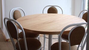 A dining area with a round wooden table, six metal chairs, and a hanging pendant light.