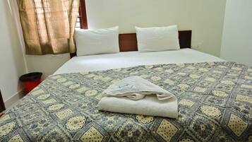 Una cama bien hecha con una colcha estampada, dos almohadas y una toalla doblada sobre la cama.