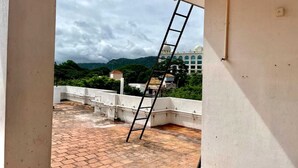 A room with a view of a building and greenery. A ladder is leaning against the wall. - Bricknest Homes (Mysore)