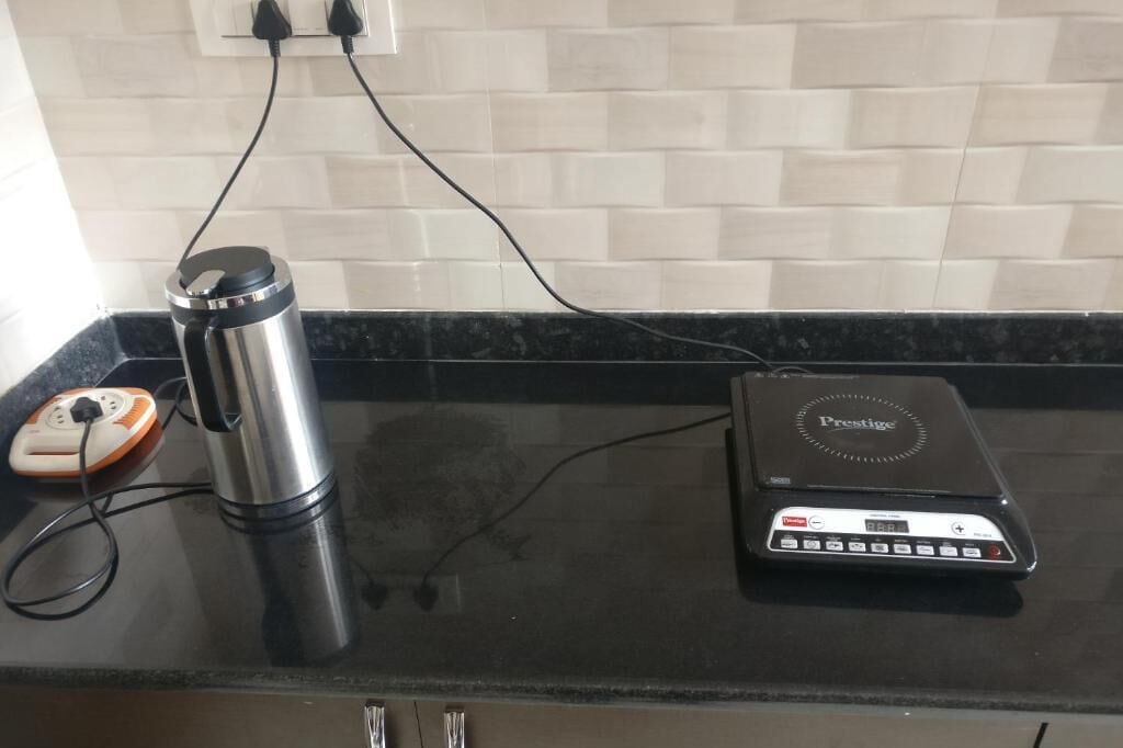 Una encimera de cocina con un dispensador de agua de acero inoxidable, una balanza digital y una regleta de enchufes.