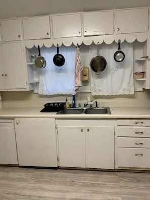 A kitchen with white cabinets, a sink, and hanging pots. - Cozy Three Bedroom House In Scenic Rusk. (Rusk)