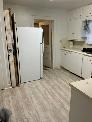 A kitchen with a white refrigerator, wooden cabinets, and a tiled floor. - Cozy Three Bedroom House In Scenic Rusk. (Rusk)
