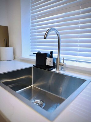 A modern kitchen with a stainless steel sink, a faucet, and a soap dispenser. - Large 4BR Home w/3 Baths I Sleeps 9 I Free Parking (South Croydon)