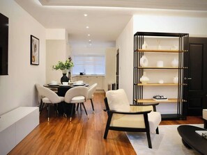 A modern living room with a dining area, a bookshelf, and a sofa.