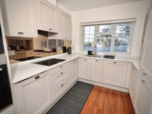 A modern kitchen with white cabinetry, a black countertop, and a window with blinds. - Large 4BR Home w/3 Baths I Sleeps 9 I Free Parking (South Croydon)
