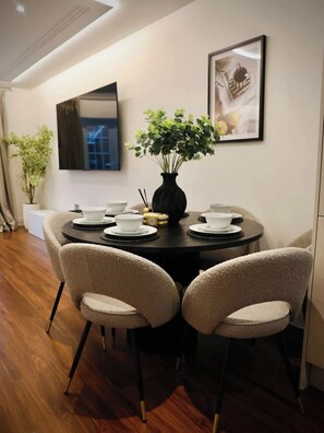 A dining area with a round table, four chairs, a vase with green foliage, and a framed picture on the wall. - Large 4BR Home w/3 Baths I Sleeps 9 I Free Parking (South Croydon)