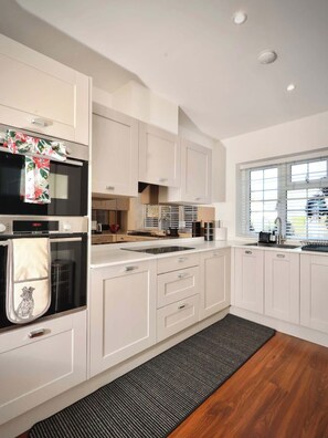 Una cucina moderna con mobili bianchi, forno integrato e una finestra che offre luce naturale.