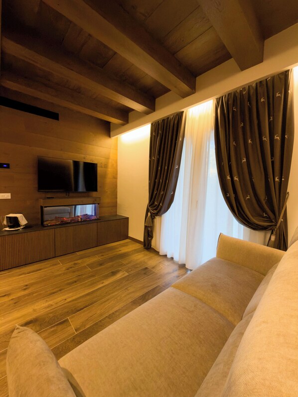 Una sala de estar moderna con techo de madera, televisor de pantalla plana, sofá y cortinas.