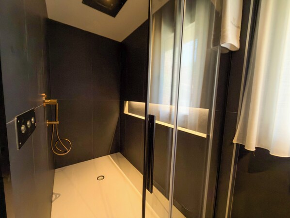 A modern shower with a glass door, a control panel, and a towel rack. - Luxury Mountain Suites (Roccaraso)
