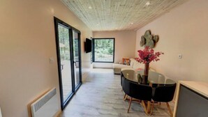 A modern interior with a glass table and chairs, a sofa, and a TV mounted on the wall. - New 2CH gîte with private pool - Peace, nature & comfort 10min from Bergerac (Lembras)