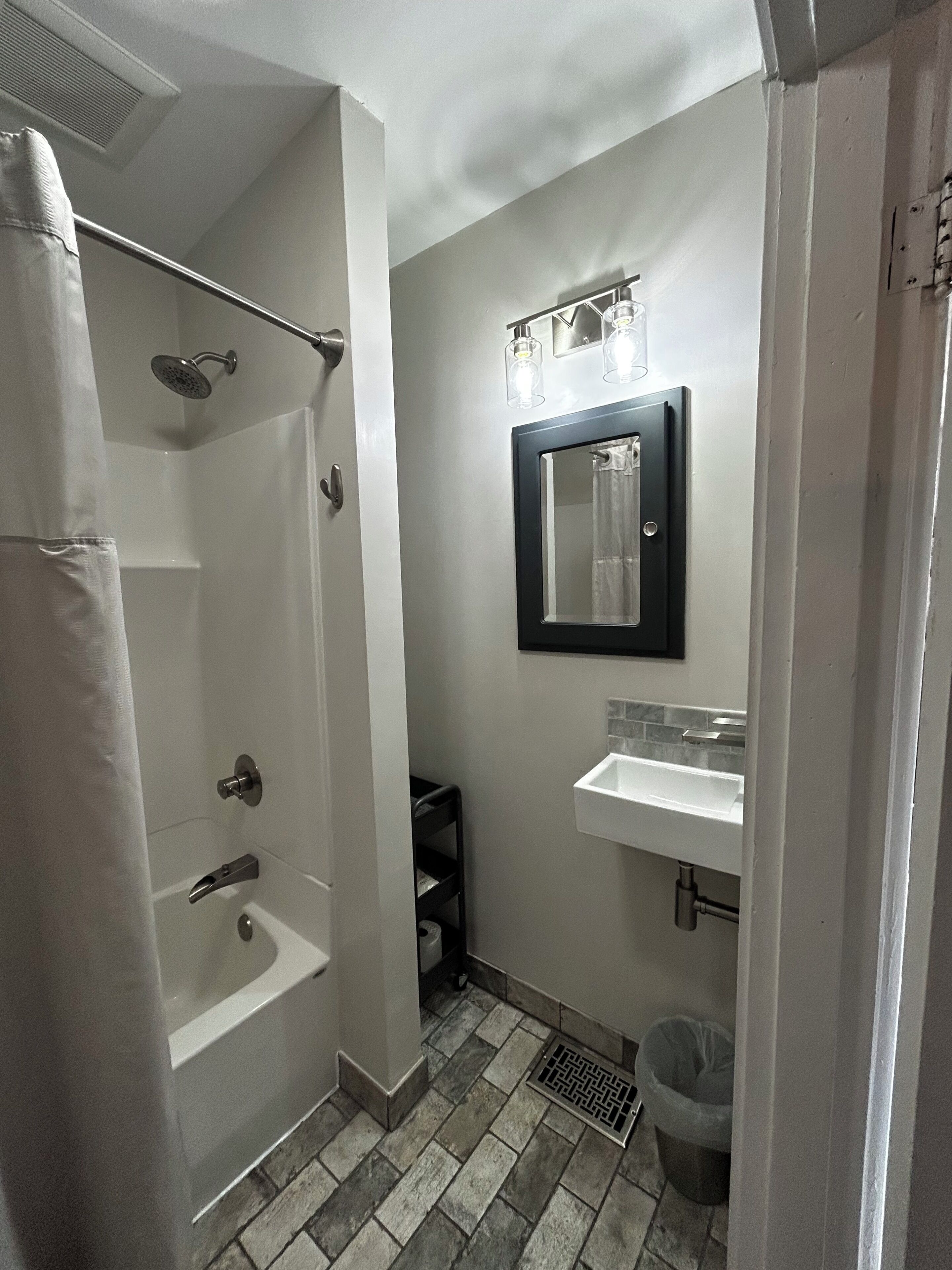 A bathroom with a shower, a sink, and a mirror.