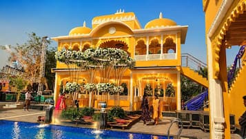 A hotel with a pool, a fountain, and a traditional architectural style.