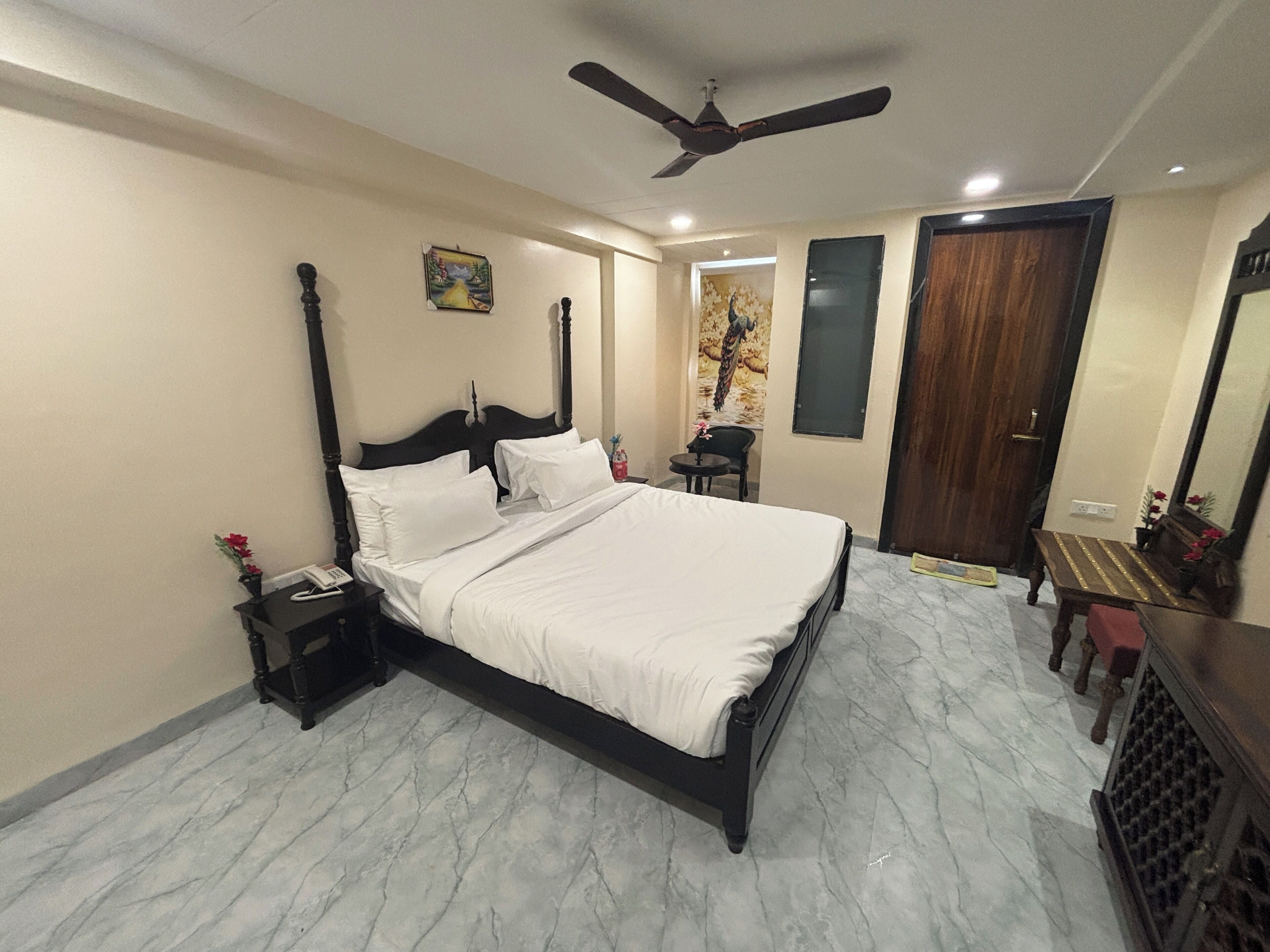 Un dormitorio ordenado con una cama grande, una mesita de noche, una silla y una pequeña mesa.