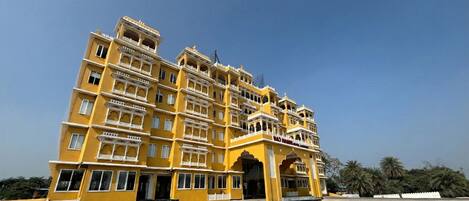 A multi-story building with a yellow facade and ornate architectural details, including balconies and arches.